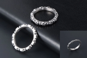 Macro detail of silver stainless steel skull pattern rings on black leather background