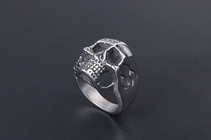 Detail of silver titanium steel skull ring featuring punk flame engraving and metal texture