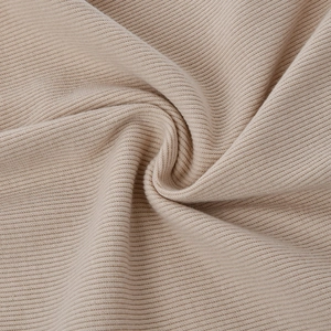 Dettaglio macro del tessuto a costine beige con luce soffusa e pieghe a spirale naturali