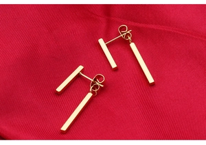 Detail of minimalist 18k rose gold plated bar earrings on elegant red fabric