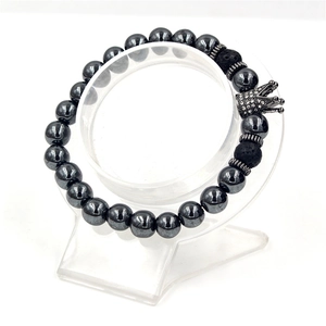 Macro view of elastic beaded bracelet with a diamond crown charm and silver spacers