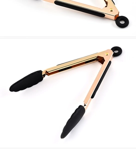 Detail of gold-plated food tongs with black silicone tips and round hanging ring hook