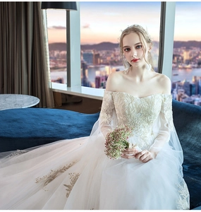 Close-up of elegant off-shoulder wedding dress with intricate gold floral lace embroidery