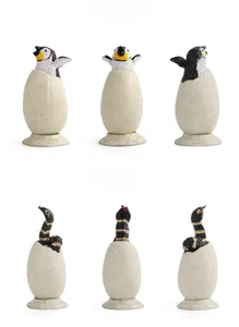 Detailed realistic models of penguin and snake hatching from eggs on white background