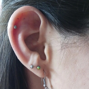 Detail of 316L stainless steel studs and ball earrings worn on different ear parts