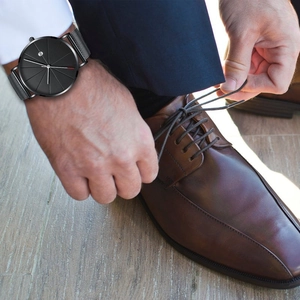 Detail of minimalist men's business watch with black mesh strap and date display function