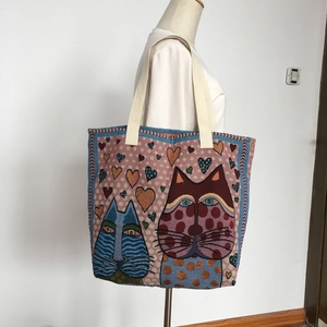 Pink canvas tote bag featuring blue cat patterns shown on a model in a casual setting