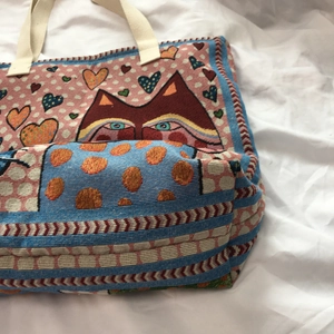 Detail view of woven cat and heart pattern on multi-color canvas shoulder bag