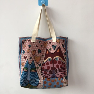 Detail of woven tapestry tote bag with stylized cats, hearts and beige cotton straps
