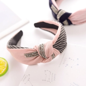 Close-up of pink fabric headband with rhinestone knot and striped lining detail