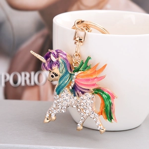 Sparkling unicorn keychain with colorful enamel and crystals on a white ceramic cup