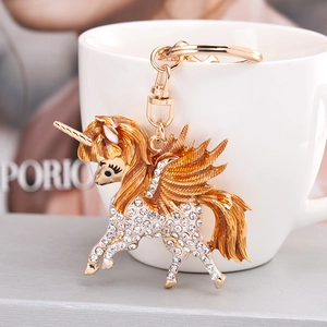 Sparkling unicorn keychain with white rhinestones and gold enamel hanging on a cup