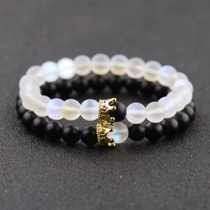 Close-up of moonstone and matte black couple crown bracelets with gold pave details
