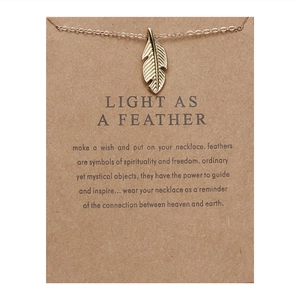 Detail of gold feather pendant necklace on a kraft paper gift card with English text