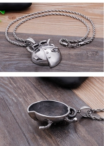 Detailed macro view of mechanical heart pendant with rope chain on dark wood background