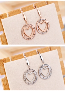 Détail de boucles d'oreilles cœur creux en or rose et argent avec strass scintillants