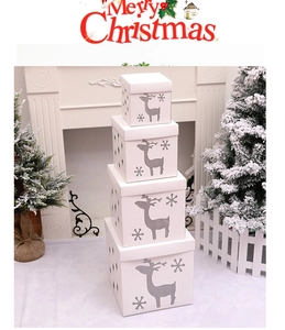 Stack of white nested Christmas gift boxes featuring reindeer and snowflake cutouts