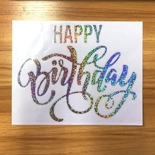 Detailed view of iridescent rainbow holographic Happy Birthday sticker on wooden background