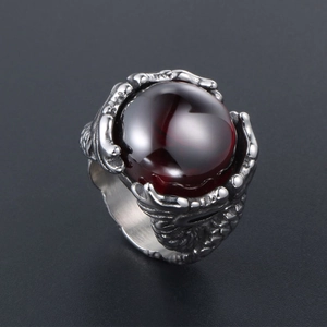 Vintage stainless steel dragon claw ring featuring a large red gemstone on dark background