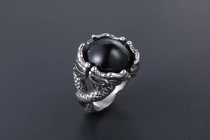 Macro shot of silver dragon carving grasping a large round black gemstone on a men's ring