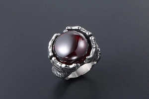 Macro detail of vintage dragon claw ring featuring a large red gemstone and silver texture