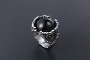 Detail of vintage dragon claw ring featuring a large polished black gemstone and scales
