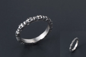 Macro detail of silver titanium steel ring featuring continuous skull relief design