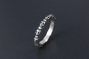Macro view of sterling silver skull band ring with detailed 3D skeletons on dark surface