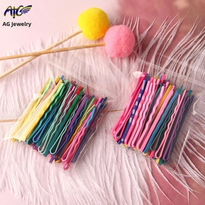 Close-up of colorful wave-shaped metal hairpins set on soft white feathers background