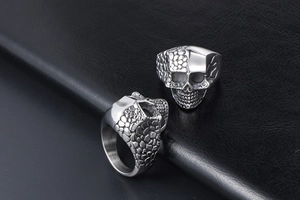 Macro shot of silver stainless steel skull rings on black leather texture