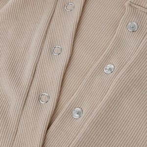 Dettaglio della trama in maglia a costine e bottoni automatici in metallo su body beige