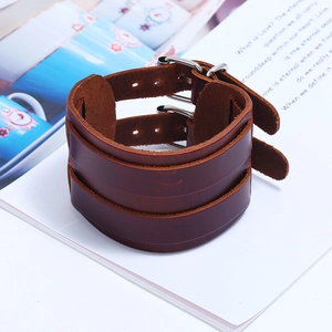 Macro shot of broad brown leather wristband with double silver metal buckles on a book
