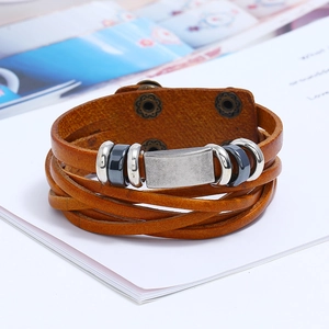Detail view of a vintage brown woven leather bracelet with aged metal clasps on book pages