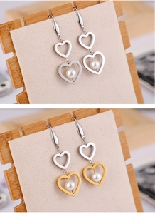 Vue détaillée de boucles d'oreilles double cœur en titane avec perle et finitions