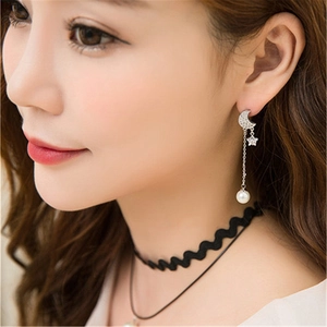 Close-up of moon star long earrings with white pearls and a black wavy choker
