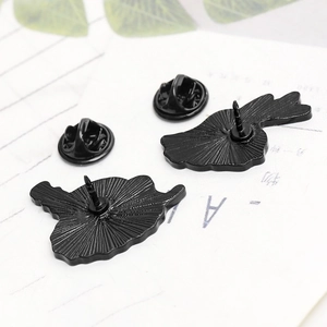 Macro detail of black enamel pin backs featuring anti-slip texture and butterfly clutches