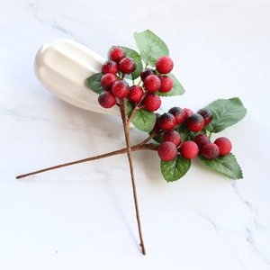 Artificial Christmas red berry branches in white ceramic vase on marble tabletop