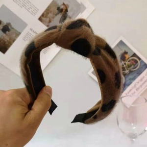 Close-up of soft plush leopard print headband in brown with black dots pattern