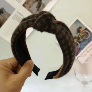 Detail of a brown plaid plush knotted headband featuring soft fabric texture and wide design