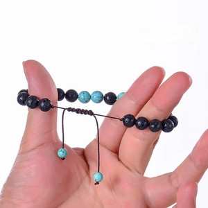 Dettaglio del bracciale con perline di lava da 8mm e corda intrecciata sulla mano