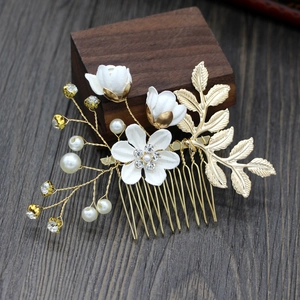 Detail of bridal hair comb with white fabric flowers, pearls, and rhinestones on gold metal