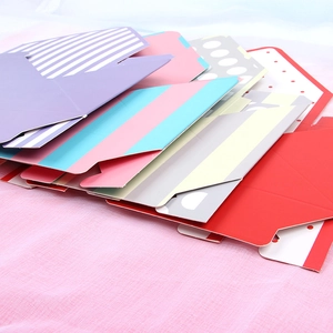 Assorted colorful envelope flower gift boxes with various patterns on pink fabric background