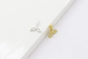 Detailed view of sterling silver whale tail pendants with sparkling zircon stone inlays