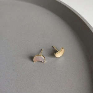 Detailed close-up of crescent moon earrings with golden edges and shell inlay on grey tray