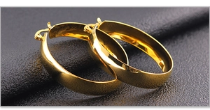 Macro shot of thick gold hoop earrings with mirror finish on black leather surface
