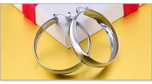 Macro shot of wide-band silver hoop earrings with a high-polished mirror finish