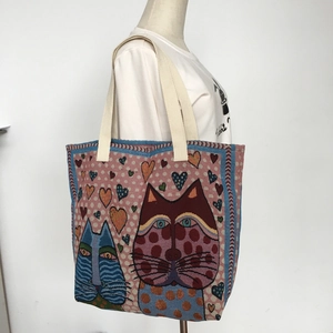 Artistic cat illustration on a canvas tote bag shown worn by a model against a white wall