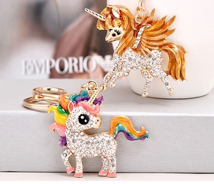 Macro detail of gold-plated unicorn keychains with sparkling crystals and rainbow mane