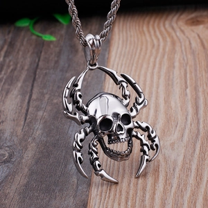 Vintage punk stainless steel spider and skull pendant necklace on a wooden background