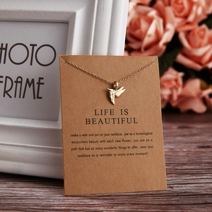 Detail of a gold hummingbird necklace on a brown Kraft gift card with sentimental text